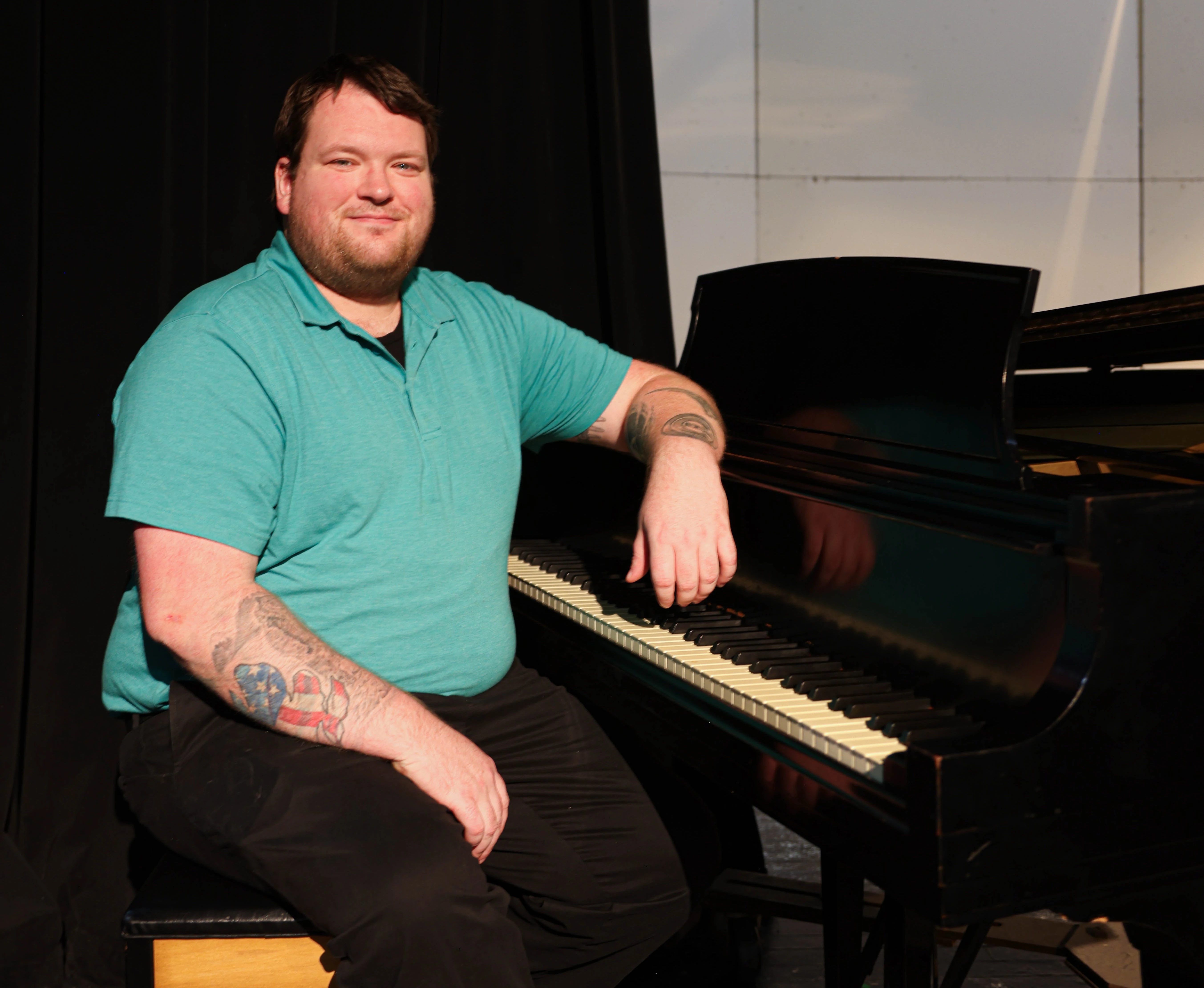 Nathan Helm sits at the piano in a Mount Mercy music room