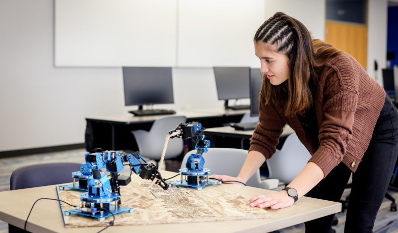 娜塔莉·普里姆斯25岁 observing robotic arms in the middle of Basile Hall's Data Science computer lab