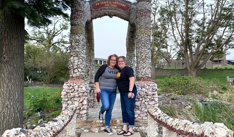 Kim Smith and Catherine standing beside the grotto in the greenspace in 皇冠体育
